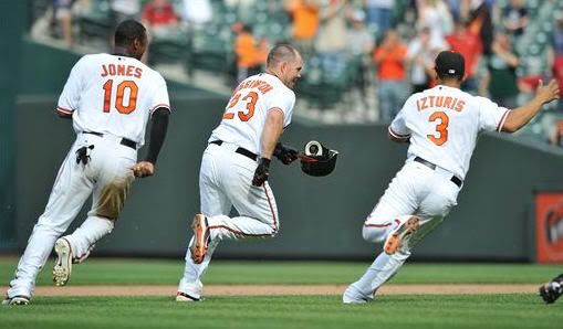 Baltimore Orioles Ty Wigginton, center, runs away from Adam Jones and Cesar Izturis after he drove in the winning run against the Boston Red Sox during the 10th inning of a baseball game Sunday, May 2, 2010 in Baltimore. The Orioles won 3-2.(AP Photo/Gail Burton)