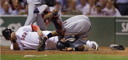 With his left shoe lying on the dirt before home plate, Cleveland Indians catcher Carlos Santana rolls after Boston Red Sox's Ryan Kalish, left, collided with him while trying to score on a single by Daniel Nava in the seventh inning of a baseball game in Boston, Monday, Aug. 2, 2010. Santana, who blocked home with his left leg, had to be carted off the field with his left leg in an air cast after the collision. (AP Photo/Charles Krupa)