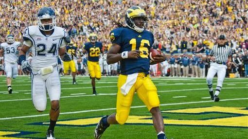 Michigan quarterback Denard Robinson (16) scores a touchdown, followed by Connecticut cornerback Dwayne Gratz (24), in the first quarter of an NCAA college football game, Saturday, Sept. 4, 2010, in Ann Arbor, Mich. (AP Photo/Tony Ding)