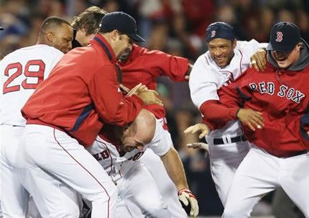 Boston Red Sox's Kevin Youkilis, center, is mobbed by teammates after his game-winning double in the 12th inning of Boston's 8-7 win over the Texas Rangers in a baseball game at Fenway Park in Boston on Wednesday, April 21, 2010. (AP Photo/Winslow Townson)