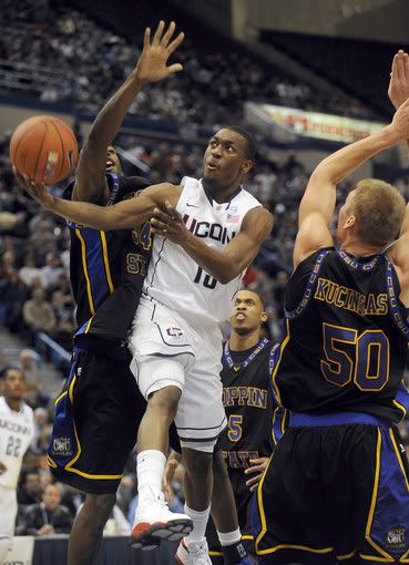 Kemba Walker of UConn got off to a slow start against Branden Doughty, left, Michael Harper, center, and Ceslovas Kucinskas, right, of Coppin State during the first half Monday night but finished with 14 points at the half as the Huskies lead 38-21. 