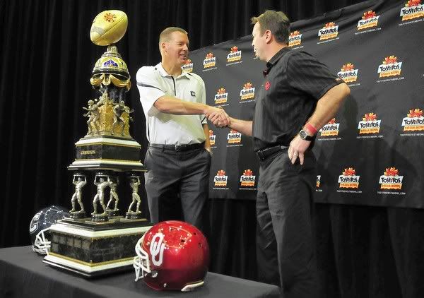 UConn head coach Randy Edsall and Oklahoma head coach Bob Stoops shake hands during press conference Friday morning with the Tostitos Fiesta Bowl trophy.