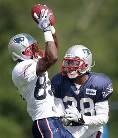 New England Patriots wide receiver Chad Ochocinco, left, holds onto a pass while being covered by teammate Darius Butler, right, during NFL football training camp in Foxborough, Mass. , Sunday, July 31, 2011.