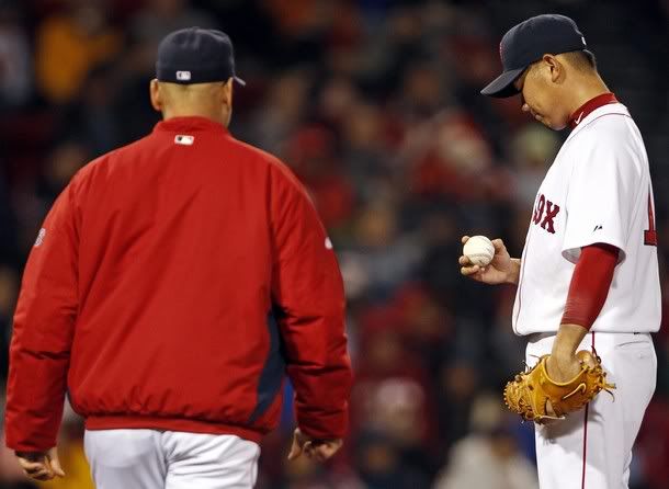 Boston Red Sox starting pitcher Daisuke Matsuzaka (R) looks at the ball as manager Terry Francona walks to the mound to remove him from the game against the Baltimore Orioles during the fifth inning of their MLB American League baseball game at Fenway Park in Boston, Massachusetts May 16, 2011.