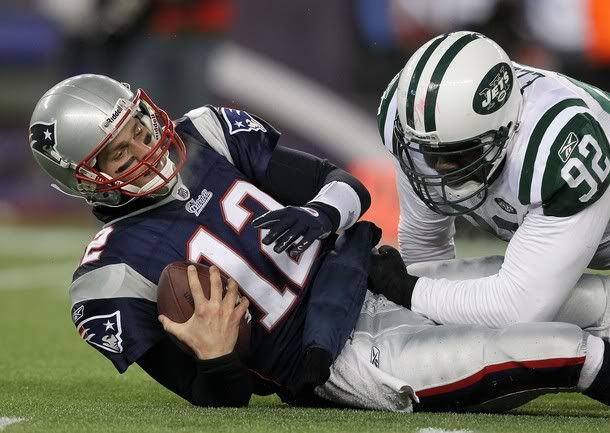 Quarterback Tom Brady #12 of the New England Patriots is sacked by Shaun Ellis #92 of the New York Jets during their 2011 AFC divisional playoff game at Gillette Stadium on January 16, 2011 in Foxboro, Massachusetts.