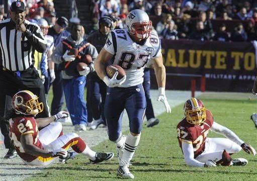 New England Patriots tight end Rob Gronkowski (87) runs past Washington Redskins strong safety DeJon Gomes (24) and Washington Redskins free safety Reed Doughty (37) during the first half of an NFL football game on Sunday, Dec. 11, 2011, in Landover, Md.