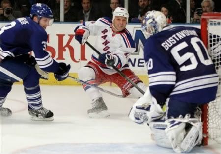 Toronto Maple Leafs defenseman Dion Phaneuf, left, watches as New York Rangers center Sean Avery (16) takes a shot on Toronto Maple Leafs goalie Jonas Gustavsson (50) in the second period of an NHL hockey game at Madison Square Garden in New York, Monday, Dec. 5, 2011.