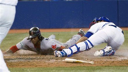Boston Red Sox pinch-runner Darnell McDonald scores past Toronto Blue Jays catcher J.P. Arencibia during the ninth inning of a baseball game in Toronto on Monday, April 9, 2012.