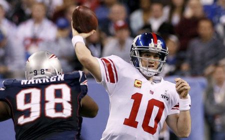 New York Giants quarterback Eli Manning passes under pressure from New England Patriots' Gerard Warren in the second quarter of the NFL Super Bowl XLVI football game in Indianapolis, Indiana, February 5, 2012.