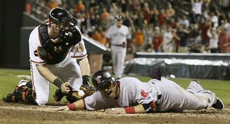 Boston Red Sox base runner Marco Scutaro (R) is tagged out at home plate by Baltimore Orioles catcher Matt Wieters in the ninth inning of their MLB American League baseball game in Baltimore, Maryland September 28, 2011.