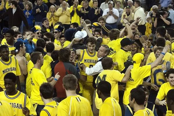 Michigan guard Zack Novak, center of crowd, is mobbed by fans rushing the court after Michigan defeated No. 15 Connecticut 68-63 on Sunday, Jan. 17, 2010, at Crisler Arena in Ann Arbor, Mich - AP Photo