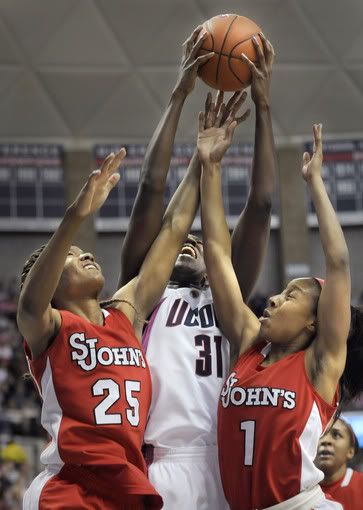 Tina Charles battles for a rebound against St. John's Joy McCorvey, left, and Sky Lindsay in the first half. On the same night her No. 31 was placed among the Huskies of Honor, Charles had a huge game -- 25 points and 21 rebounds -- to lead the No. 1 Huskies to their 64th consecutive victory (Stephen Dunn/Hartford Courant)
