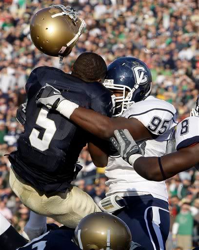 Notre Dame running back Armando Allen Jr., left, looses his helmet as he is hit by Connecticut linebacker Greg Lloyd during the second quarter of an NCAA college football game in South Bend, Ind., Saturday, Nov. 21, 2009. (AP Photo/Michael Conroy)