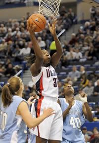 UConn's Tina Charles goes up for a basket between Rhode Island's Megan Shoniker, at left, and Ebony Evans during their game at the XL Center. - Hartford Courant Photo