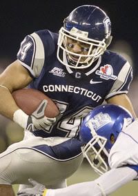 UConn's Donald Brown left, breaks through the tackle of Buffalo's Davonte Shannon during the first quarter - AP Photo